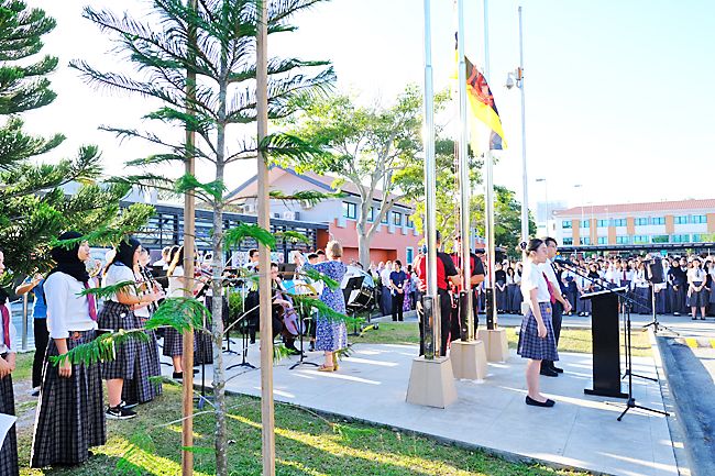 JIS Orchestra plays the national anthem as the flag is raised for 36th National Day celebration